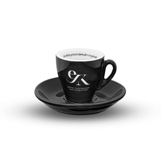 Kleine, dickwandige Espresso Tasse in Schwarz mit 65ml Inhalt, Unterteller, weißem Logo-Druck der Ersten Tegernseer Kaffeerösterei und Spruch im Tassenrand, hergestellt in Italien